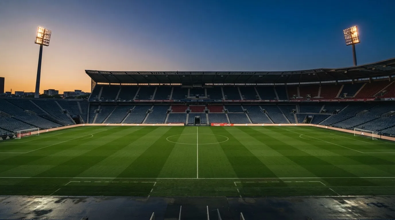 An empty football stadium with floodlight masts at dusk