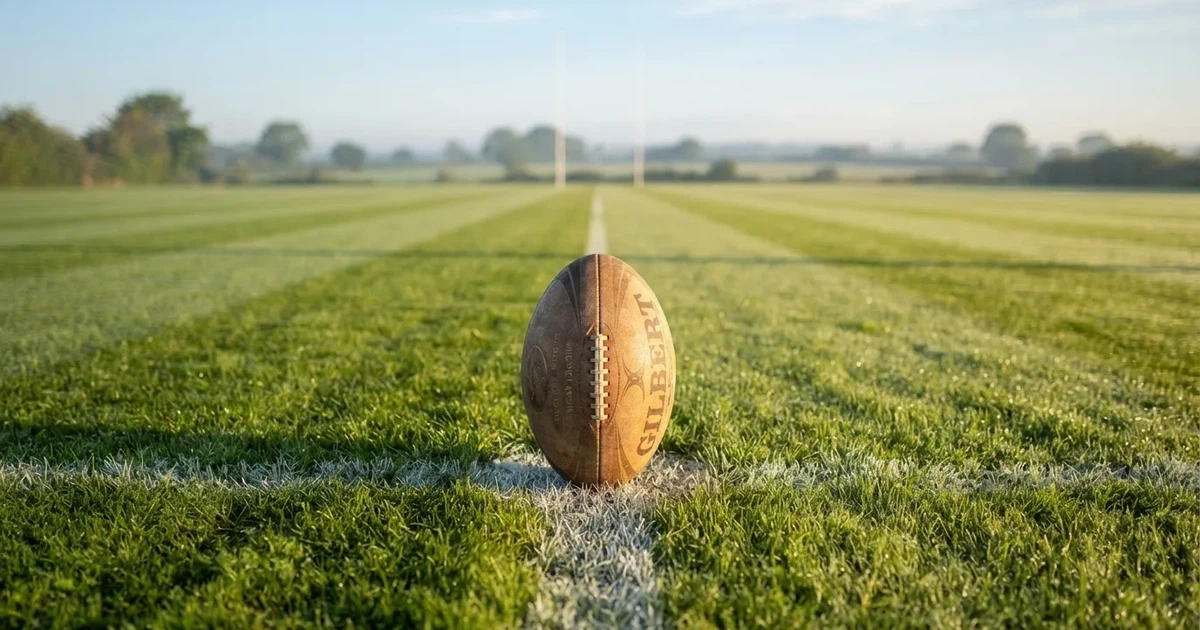 A ball on the centre spot of a grass pitch in morning light