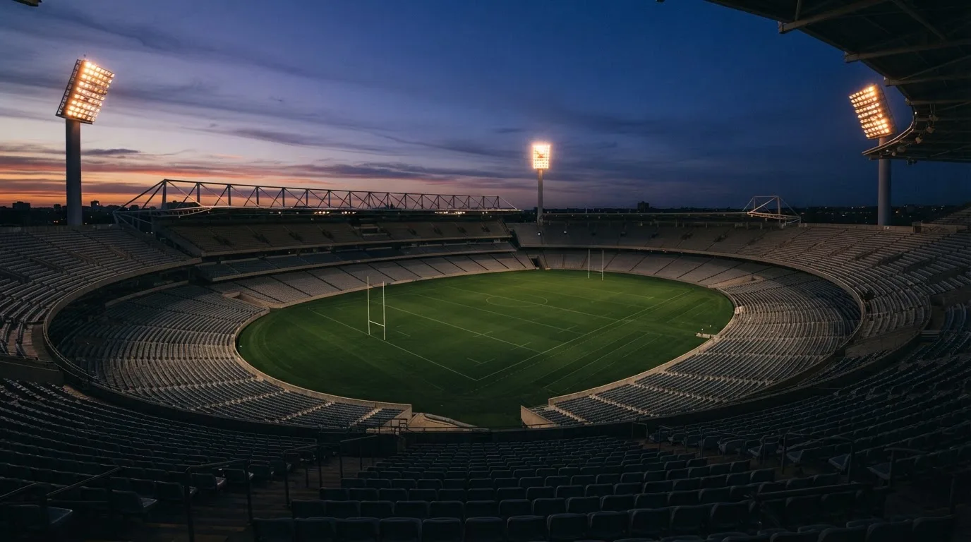 An empty football stadium with floodlight masts at dusk