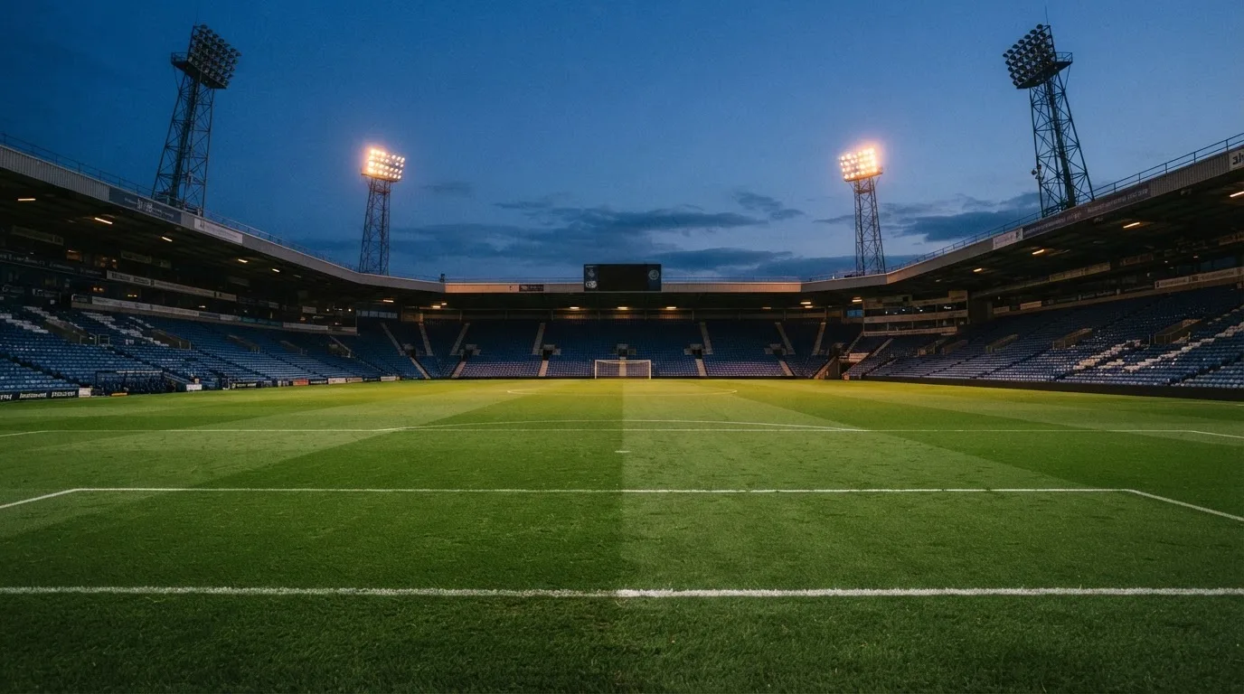 An empty football stadium with floodlight masts at dusk