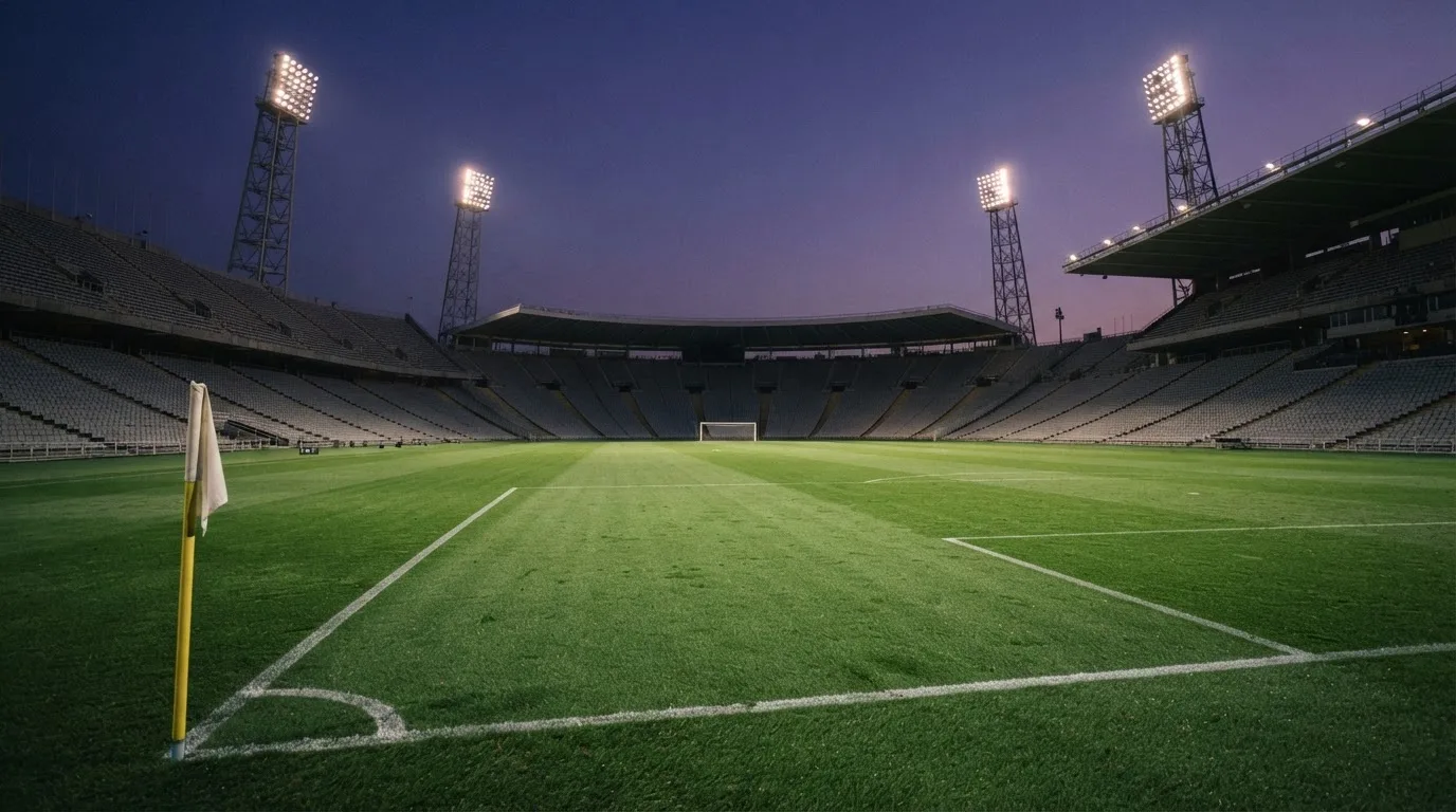 An empty football stadium with floodlight masts at dusk