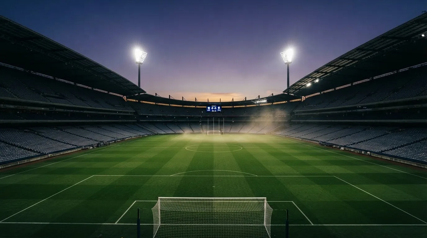 An empty football stadium with floodlight masts at dusk